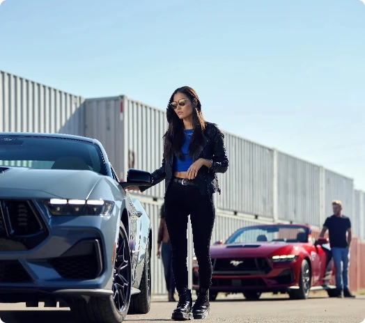 Two Ford Mustangs are lined up with their drivers standing beside them.